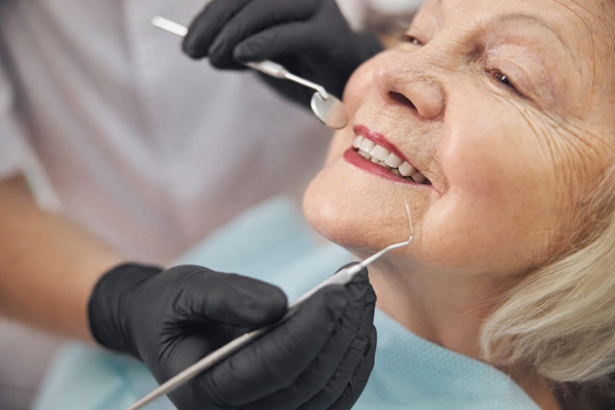 Zahnuntersuchung bei älterer Patientin: Eine Seniorin wird mit Spiegel und Instrumenten sorgfältig untersucht.
