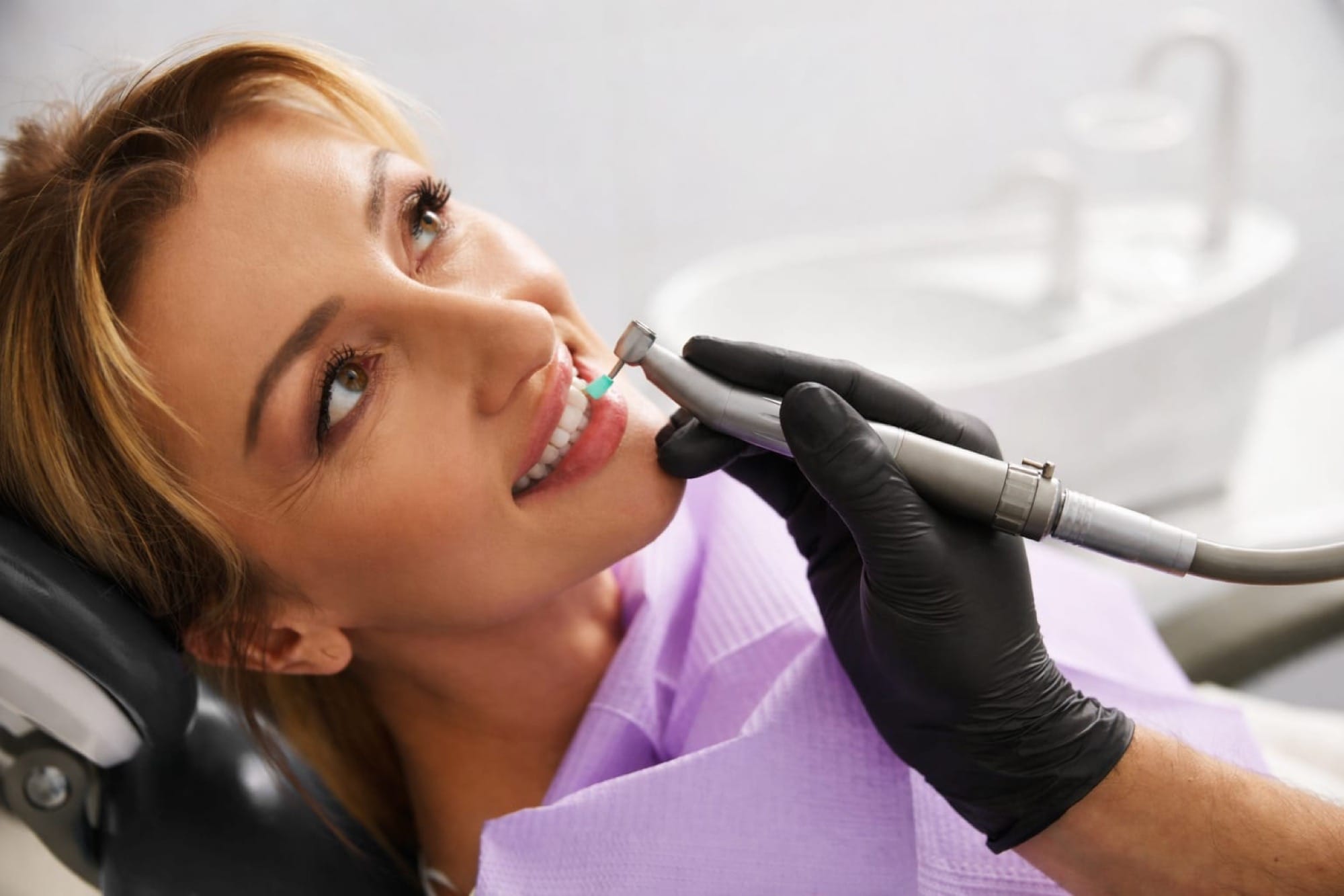 Professionelle Zahnbehandlung: Eine Frau liegt im Stuhl, während ein Zahnarzt präzise an den Zähnen arbeitet.